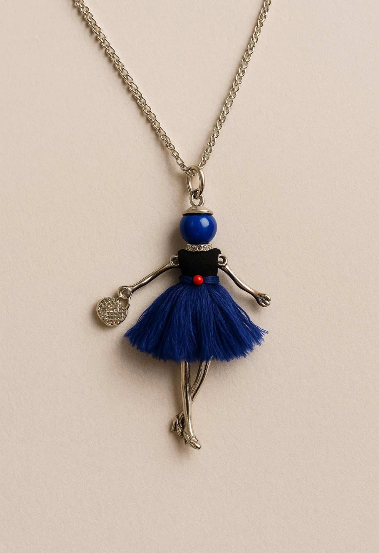 Collana lunga con ciondolo bambolina color argento e vestito blu
